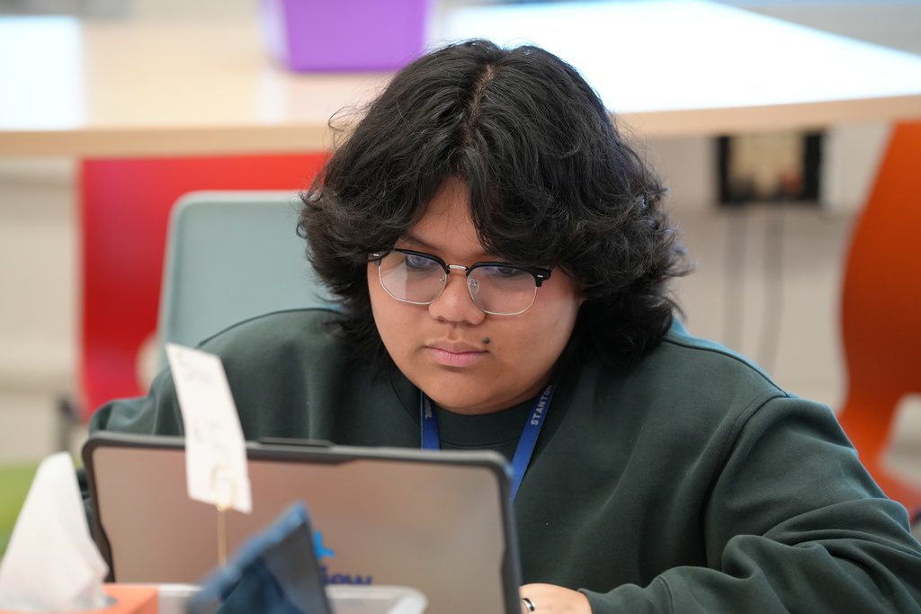 Kelly Klinger, a teacher at Stanton College Preparatory School, stands beside a student and provides guidance while the student works on a laptop in the classroom.