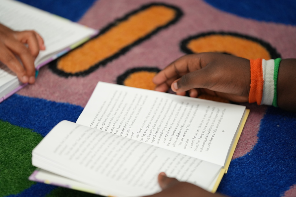 Student reads while Kadi Welty supports nearby.