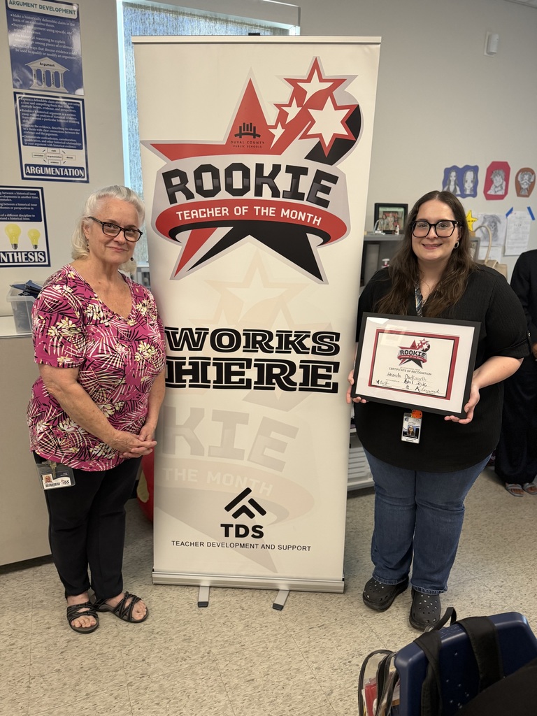 Amanda Duckworth stands next to a colleague holding her Rookie Teacher of the Month certificate in a classroom.