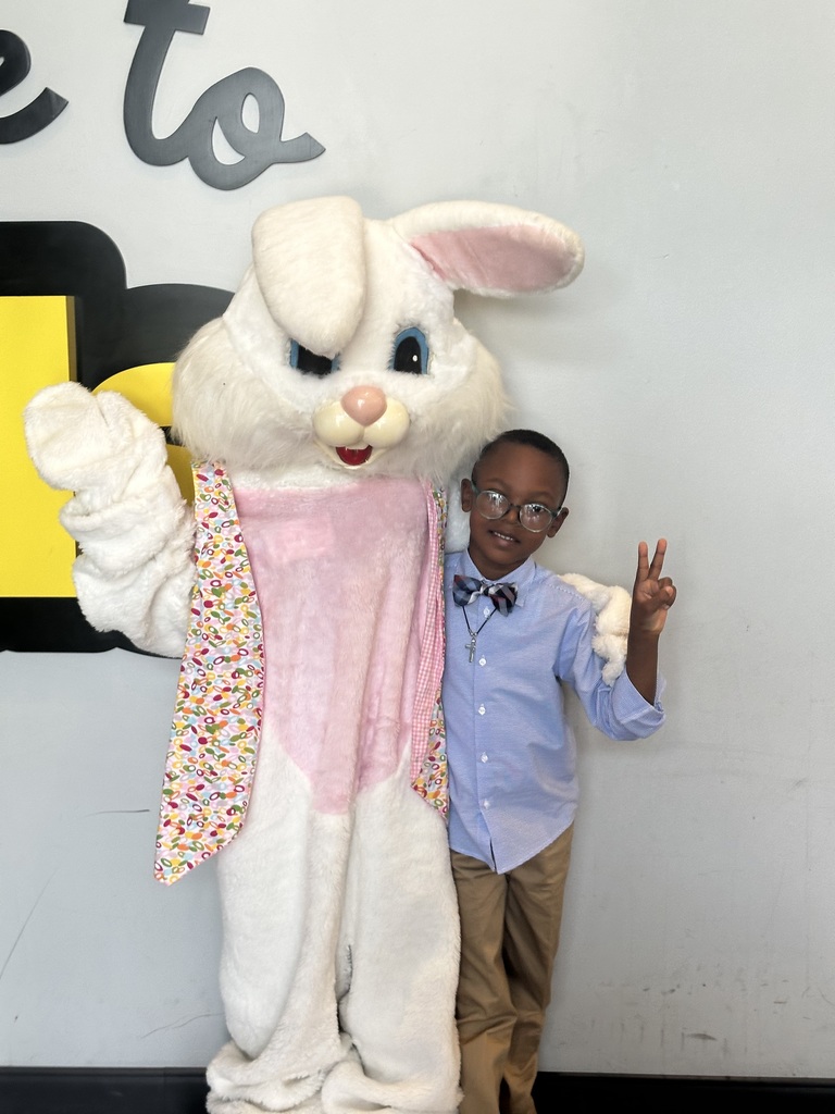 A student wearing glasses stands for a photo with the easter bunny
