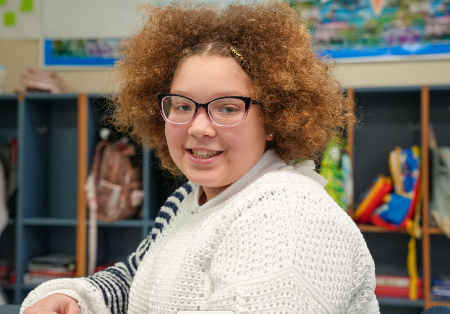 Student smiling at desk in classroom