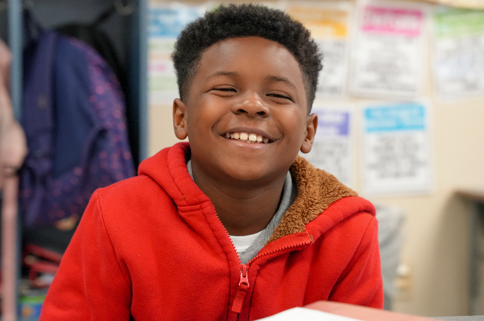 Student smiling at desk in classroom