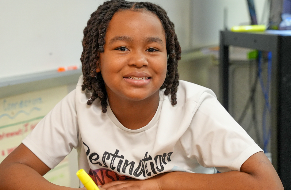 Student smiling at desk in classroom