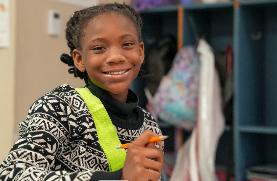 Student smiling at desk in classroom