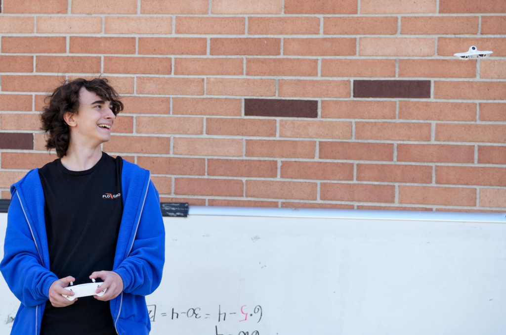 Student flying a drone outdoors on campus