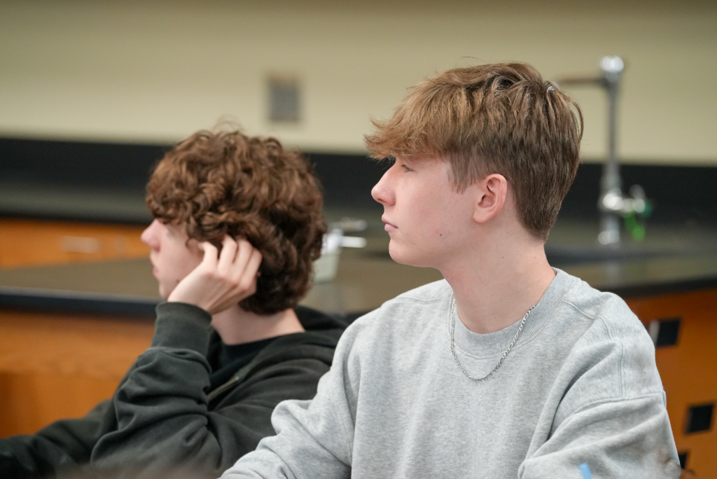 Student listens attentively during class discussion while seated at a desk.