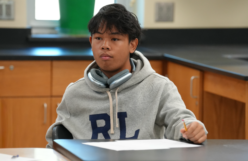 Student works with classmates during a hands-on classroom activity.