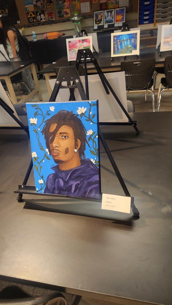 A portrait painting on a black easel displays a person in a blue outfit with flowers in the background.