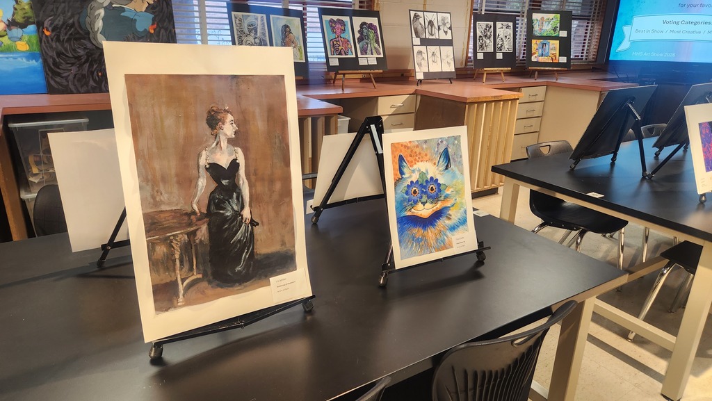 An art studio with framed paintings, including one of a woman in black, on a table.
