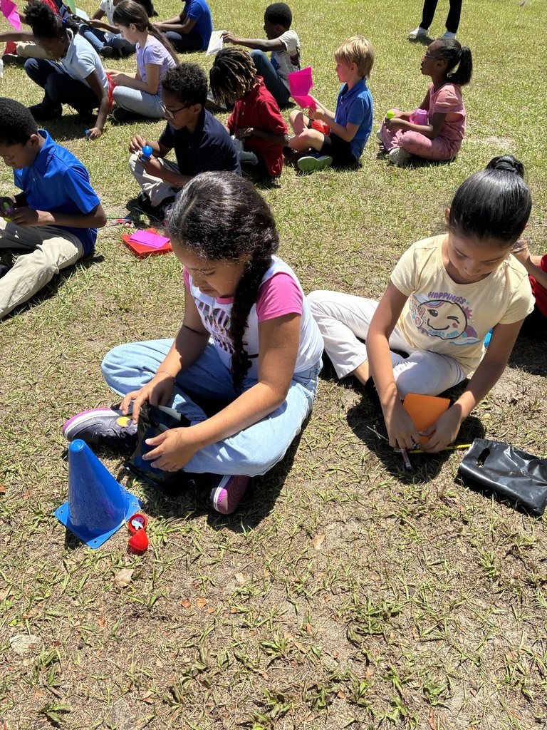 Several children sit on grass, engaged in activities. 