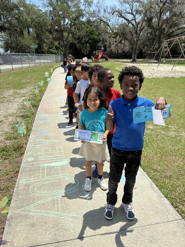 Kids stand on a sidewalk, holding certificates. 