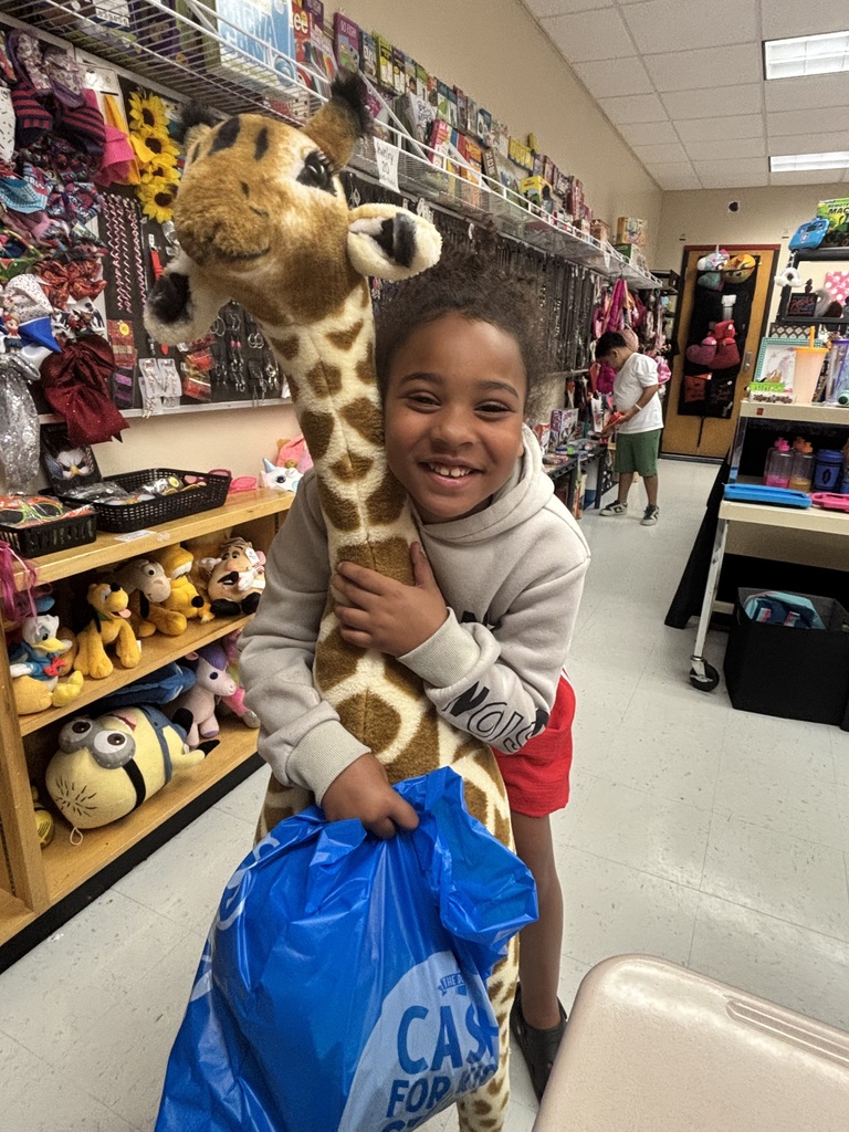 A student smiles while holding a stuffed giraffe toy