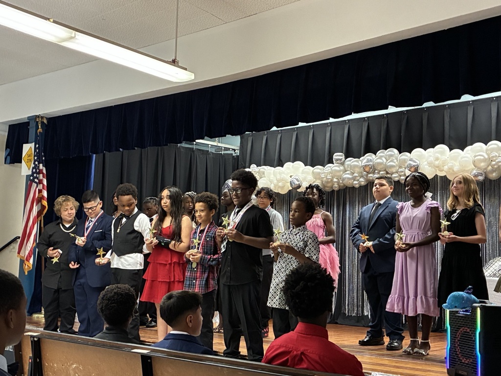 Several individuals are on stage, holding awards and facing the audience. 
