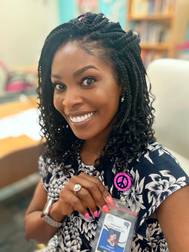 Principal Tamara Feagins smiles for a selfie, showing off her Principal badge. 