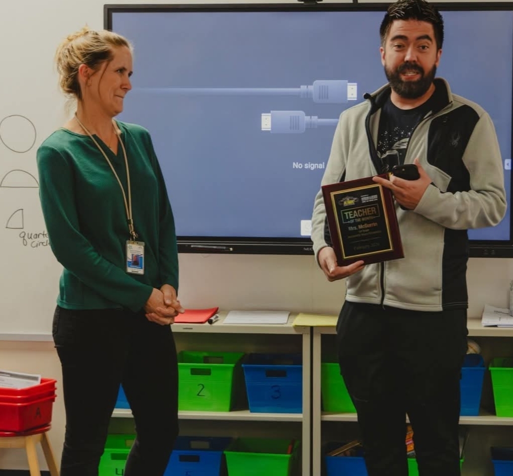 Ms. McGurrin receives a teacher of the month award from an administrator. 