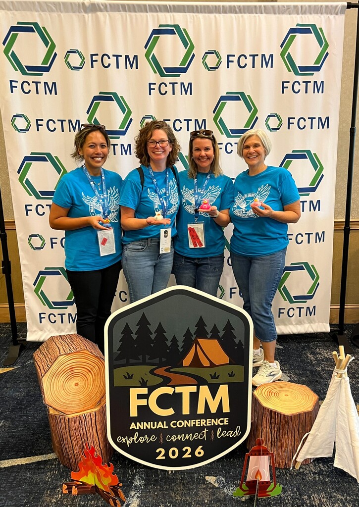 Four women stand in front of a banner and cutouts, wearing matching blue shirts. One holds a sign reading "FCTM Annual Conference 2026".