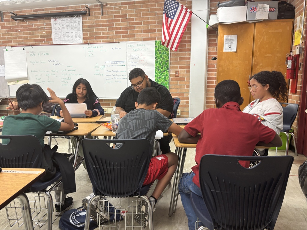 Mr. Ortiz reads at a table to a group of students.