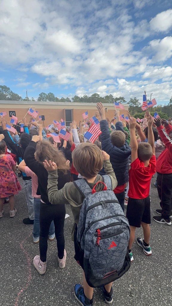 Children waving American flags in front of Mamie Agnes Jones Elementary.