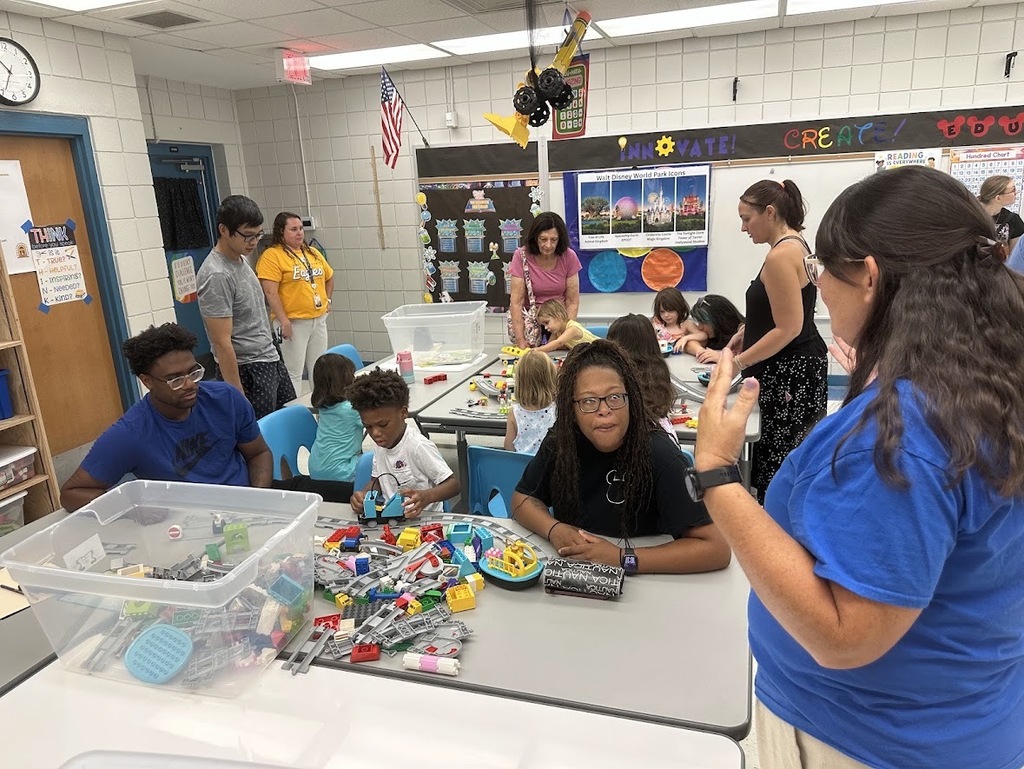 Parents and student working on LEGOs while talking to a teacher