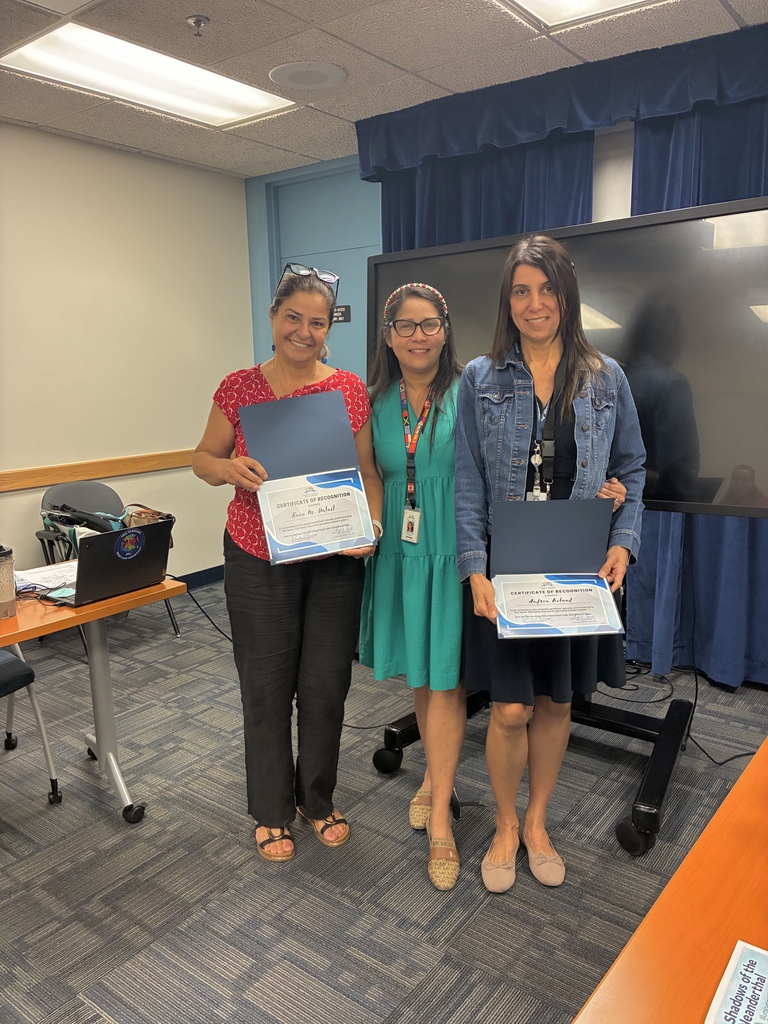 Three women stand smiling holding their award certificates.