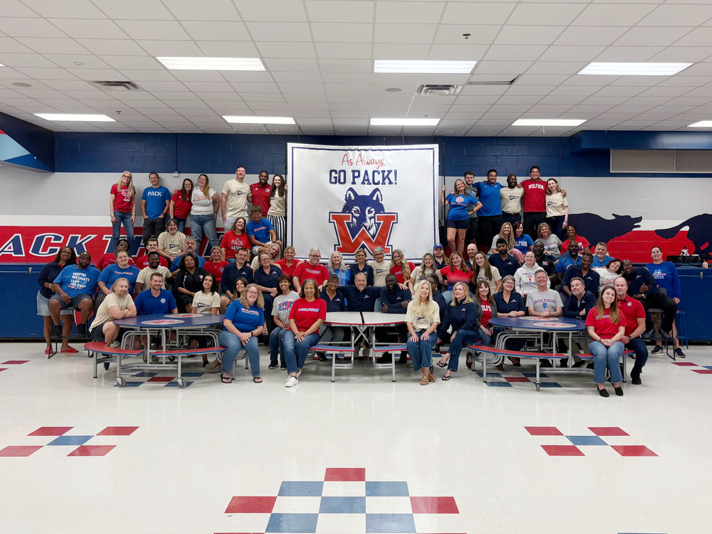 Group of people dressed in red and blue shirts posing for a picture in a gymnasium.