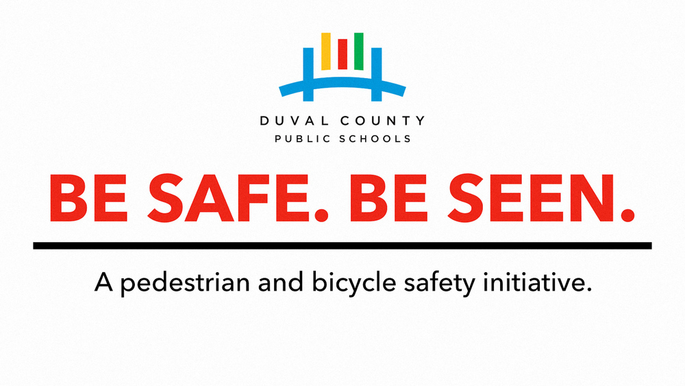 White background with blue logo. Text reads "BE SAFE. BE SEEN." Below is a smaller text, "A pedestrian and bicycle safety initiative."