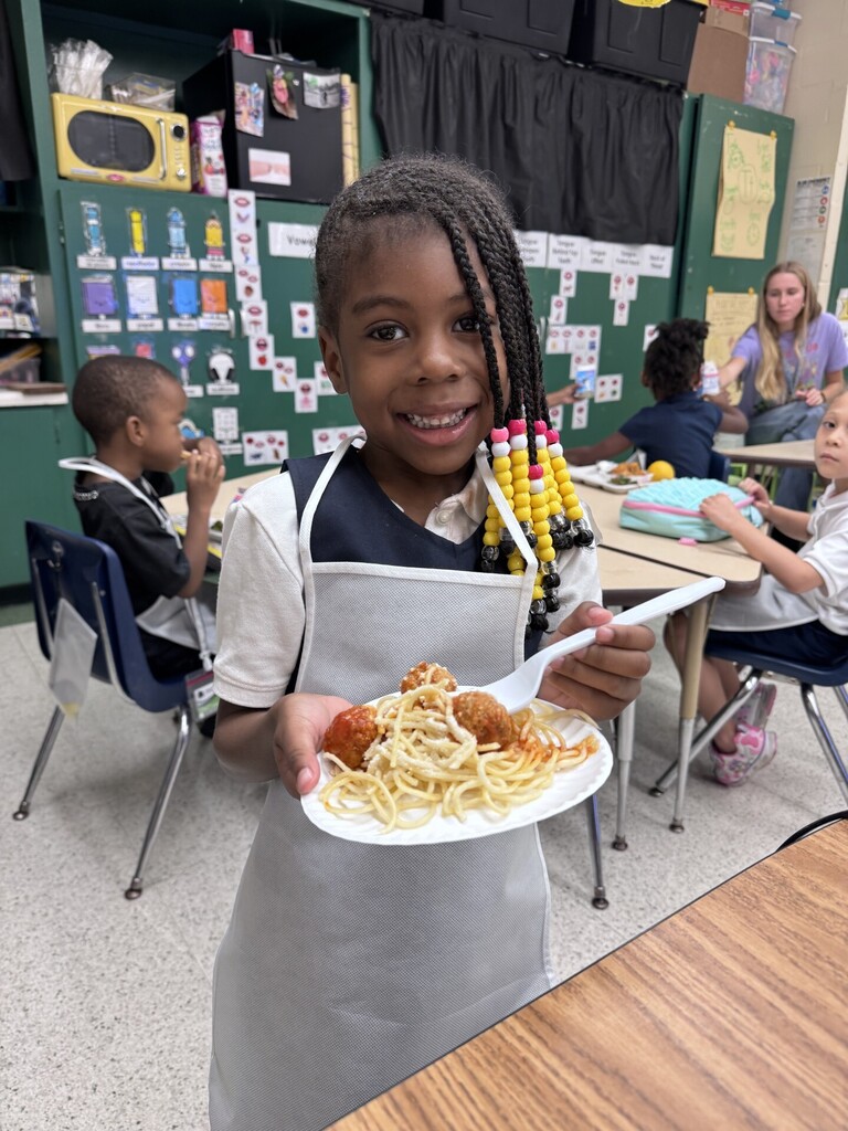 kindergartener holding a plate of spaghetti and meatballs