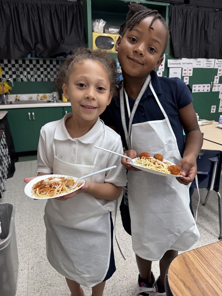 kindergarten girls holding a plate of spaghetti with meatballs