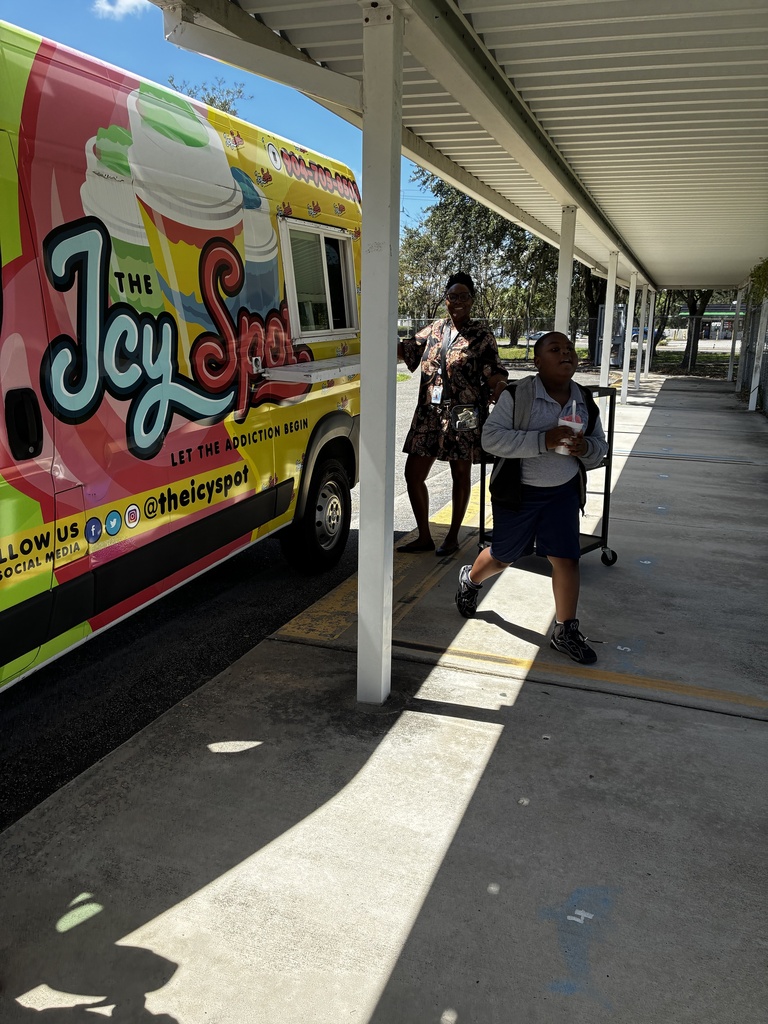 Two people stand by a colorful food truck. One person holds a backpack. The truck has yellow and purple designs.