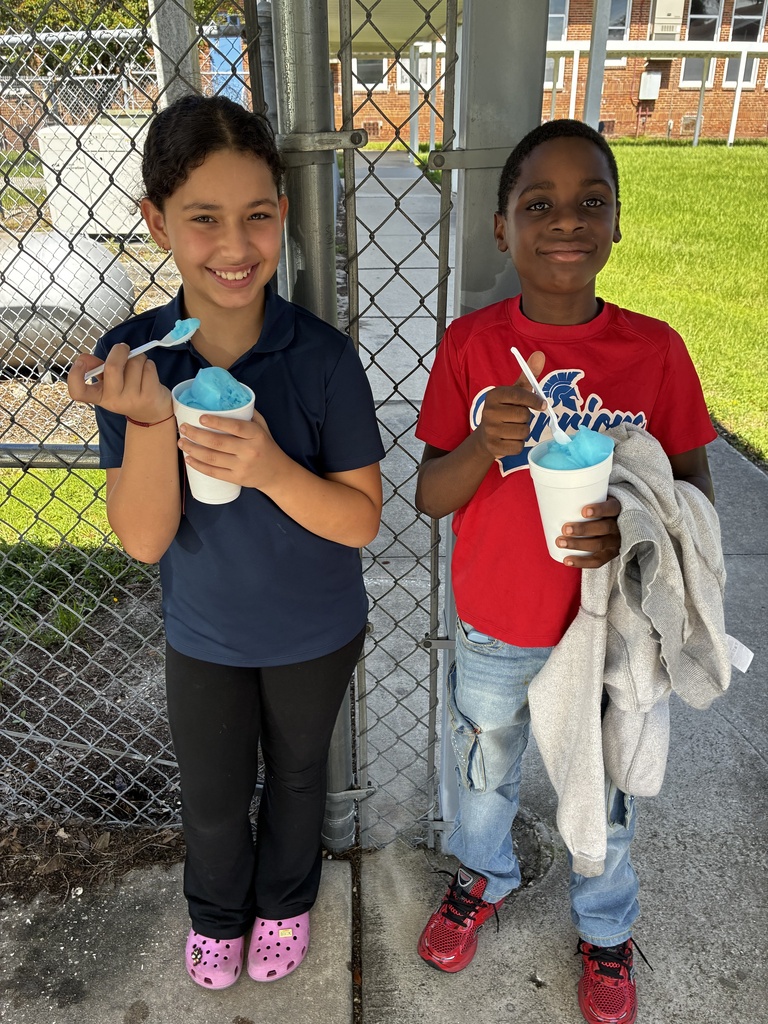 Two children next to each other, one holding a cup with a spoon and the other a cup with a straw.