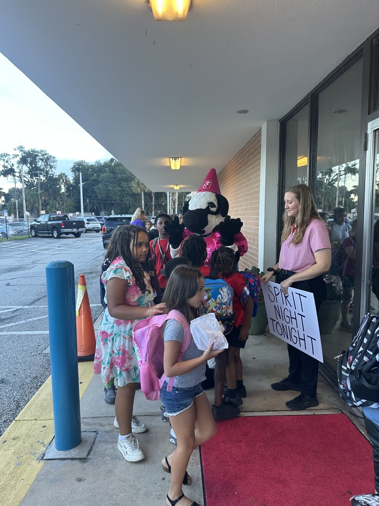 People line up outside a building, including children to see the Chick-Fil-A mascot.