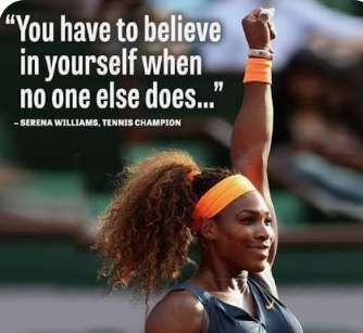 A tennis player raising her right arm, wearing a blue top, orange headband, and bracelets. Blurry people in the background.