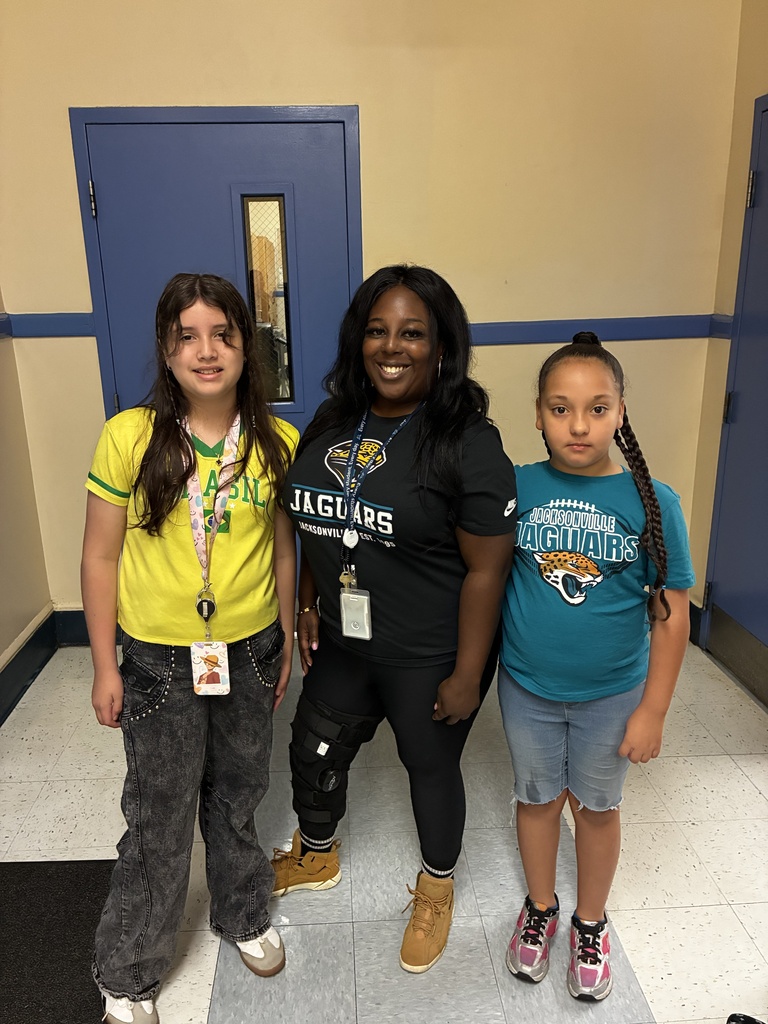 Three people in a hallway. A woman in a black shirt and one girl in blue. Another girl in yellow.