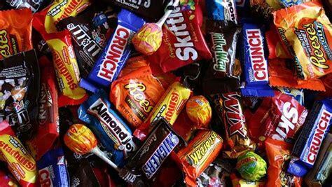 A collection of colorful candy bars and wrappers, including brands like Snickers, Kit Kat, and Almond Joy.
