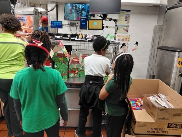guys with ties students look at an order screen at mcdonald's and tries to pack food orders from last year's school spirit night
