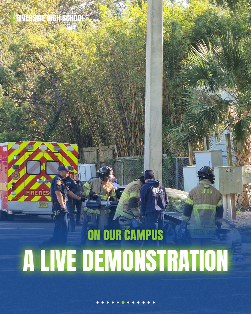 Emergency workers near a wrecked car on campus. Trees and a pole in the background.
