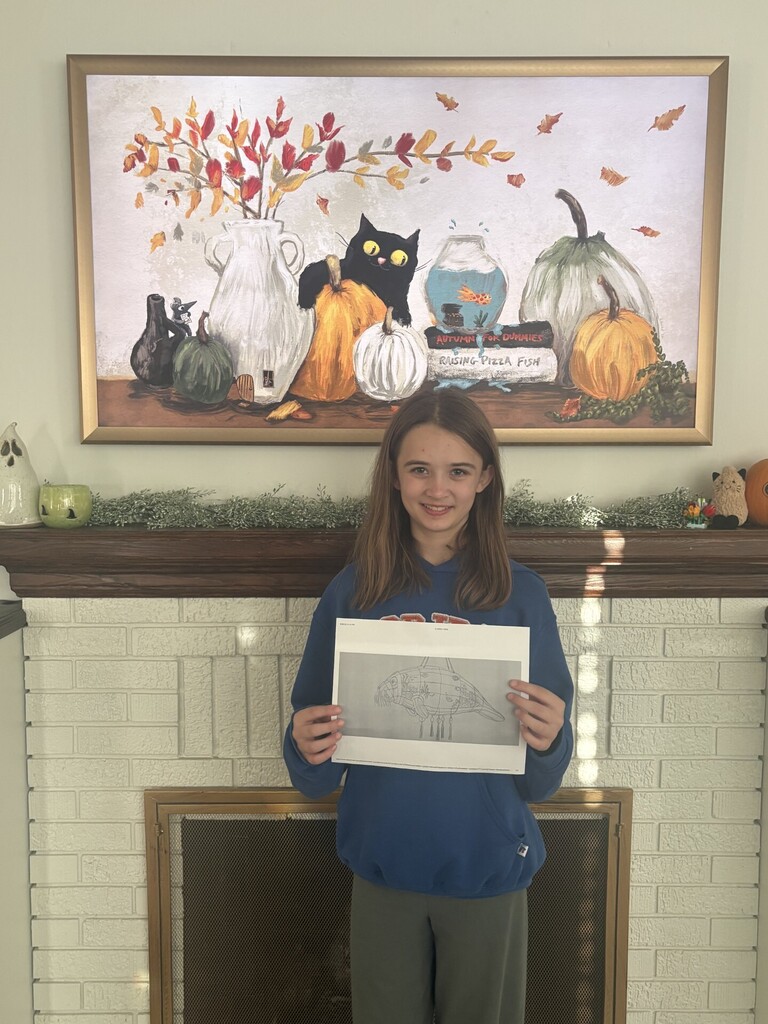 Girl holding up a drawing in front of a fireplace with a fall painting above it.
