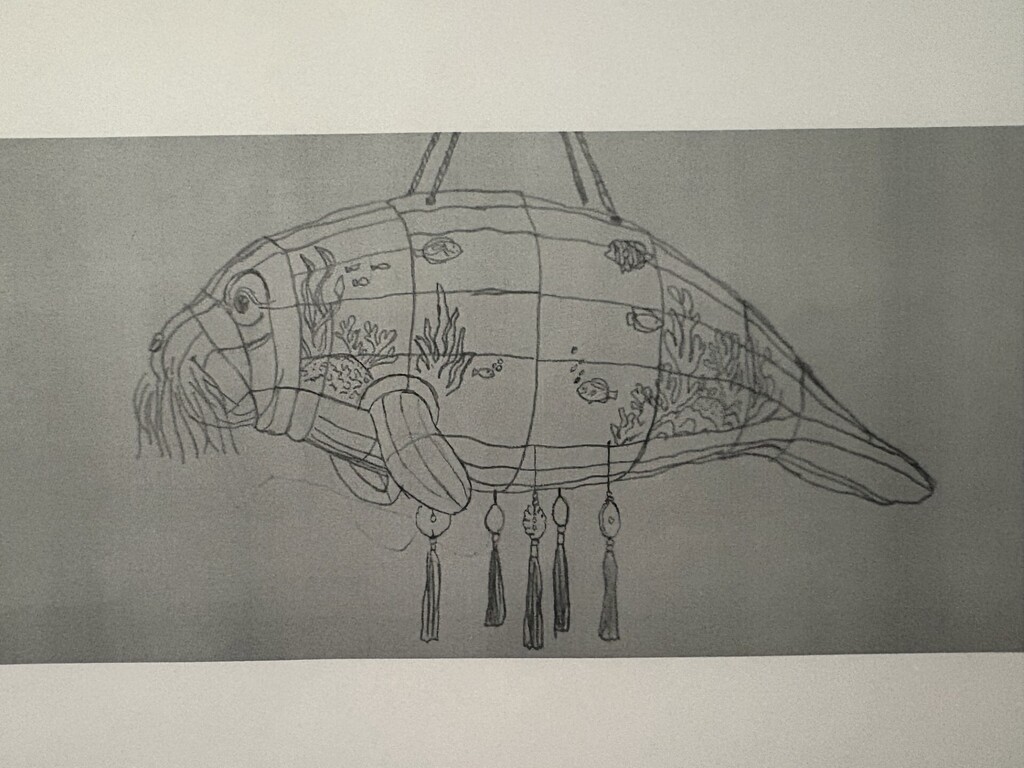 A pencil drawing of a fish-shaped structure with a grid pattern and tassels hanging from the bottom.