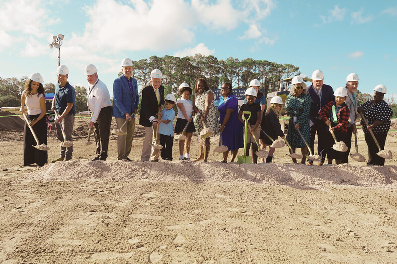 Group of people holding shovels in hard hats