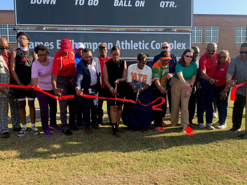 Attendees cut the ribboon in front of the new "Bob Hayes Track & Field" sign. 