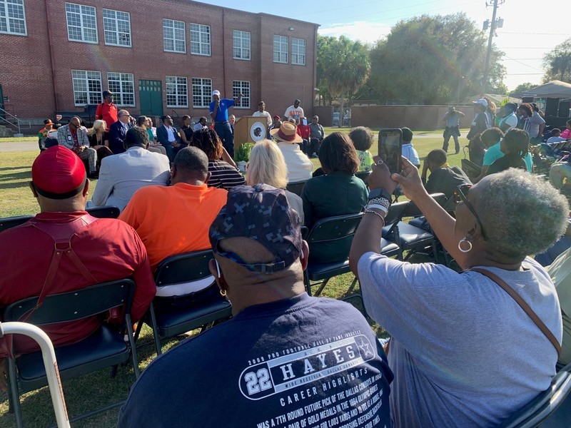 Attendees at the dedication ceremony sit facing a speaker.