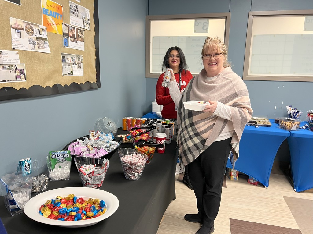 two women posing in front of table of food