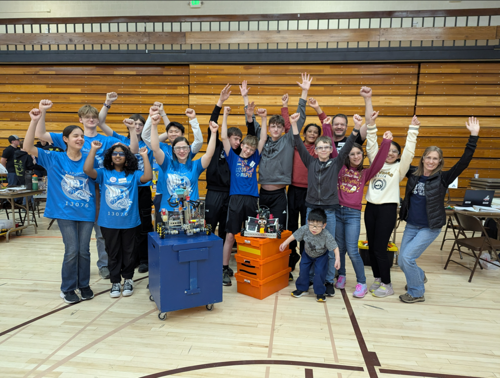 group of students celebrating behind a robot