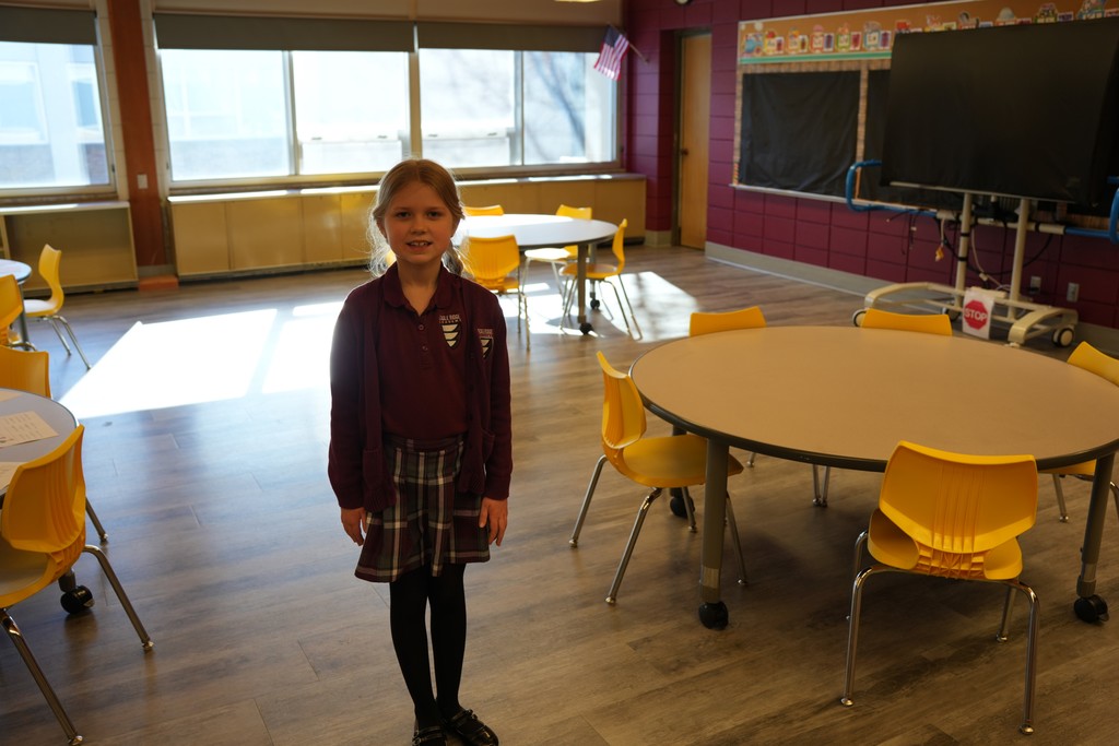 a young girl in her burgundy school uniform smiling for a picture