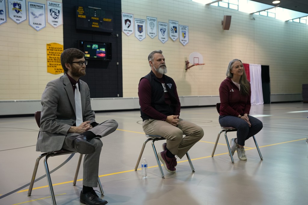 two men and a woman sitting in chairs listening to questions from the crowd