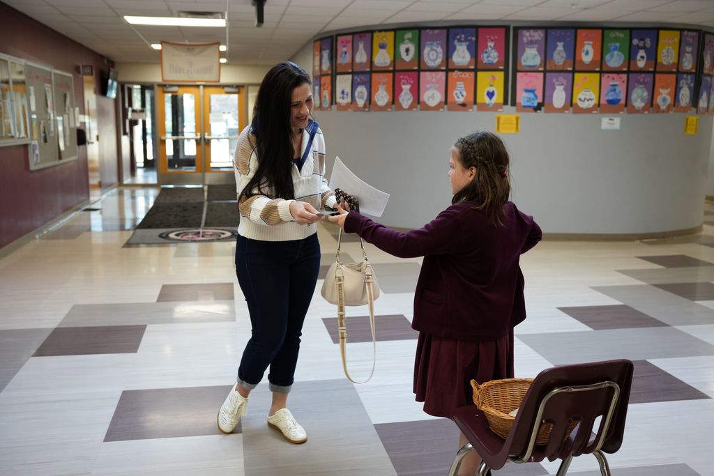 student handing pen to a volunteer