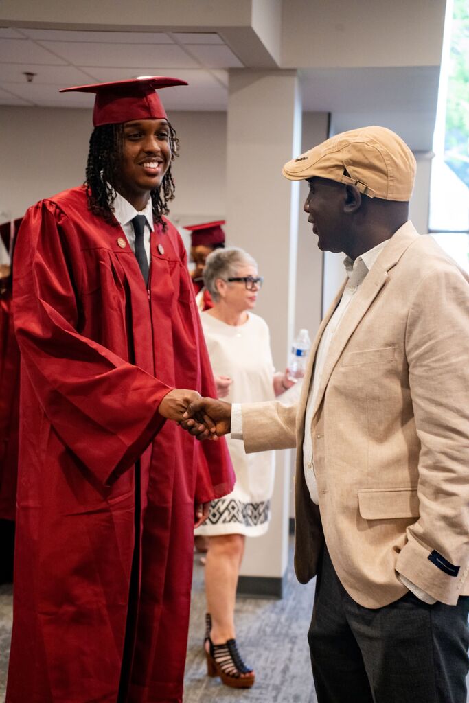 student shaking hands with adult