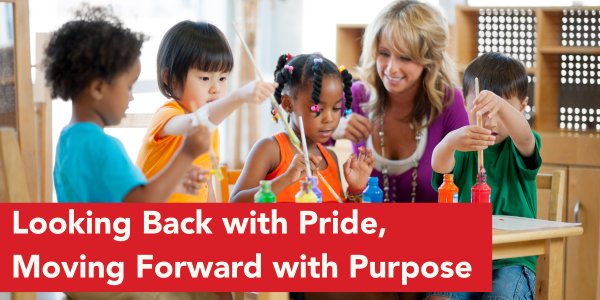 Several young children and an adult caregiver are seated together at a classroom table, participating in a hands‑on learning activity with colorful materials. A banner at the bottom of the image reads, “Looking Back with Pride, Moving Forward with Purpose