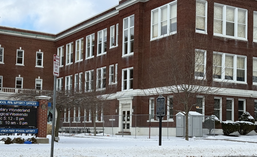 front entrance of the middle school on main street with fencing and a construction outhouse