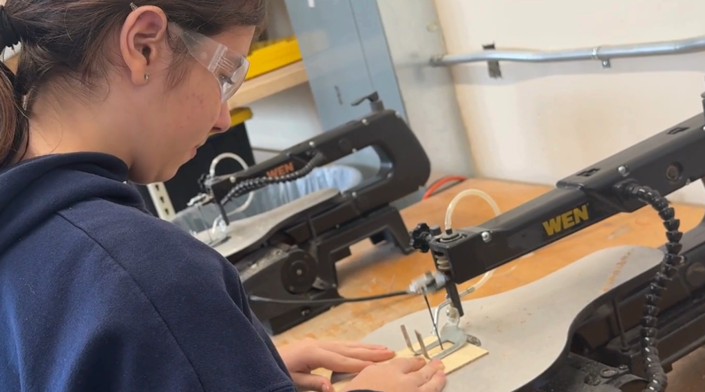 student using the jigsaw to cut the wooden pieces